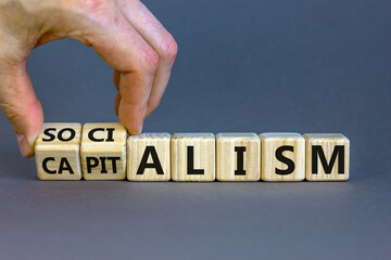 Capitalism or socialism. Hand turns cubes and changes word 'capitalism' to 'socialism'. Beautiful white background, copy space. Business and capitalism or socialism concept.