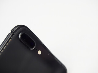 The back of modern black smartphone with a damaged curved body close-up isolated on white background