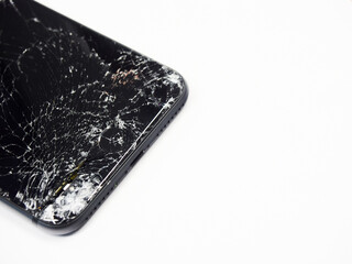 Photo of black smartphone with broken damaged display. Modern smartphone with damaged glass screen close-up isolated on white background. Device needs repair.