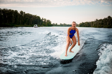 Fototapeta premium smiling woman balances on surfboard while riding the wave.
