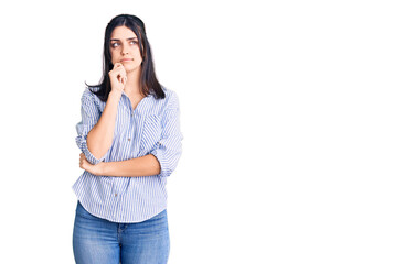 Young beautiful girl wearing striped shirt serious face thinking about question with hand on chin, thoughtful about confusing idea