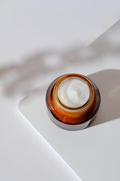 Brown amber glass jar with moisturizing cream. Natural organic cosmetic packaging design. Hand skin care concept.