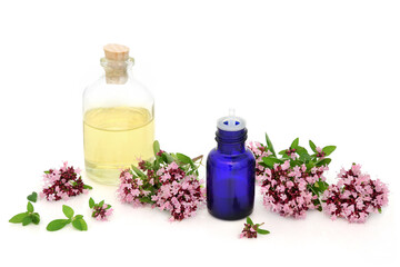 Obraz na płótnie Canvas Oregano herb flowers & leaves with essential oil bottles. Used in aromatherapy and herbal medicine. Can ease IBS symptoms, is anti bacterial, anti inflammatory, anti viral & is an anti coagulant.