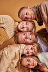 positive caucasian friends lying on heads of each other, portrait of group of attractive cheerful youth. isolated in studio