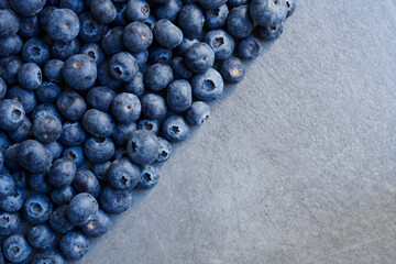 Half frame background of freshly picked organic blueberries. Winter harvest. Top view shot. Half stone texture and half blueberry.