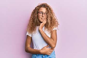 Beautiful caucasian teenager girl wearing white t-shirt over pink background with hand on chin thinking about question, pensive expression. smiling with thoughtful face. doubt concept.