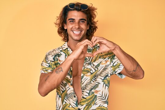 Young hispanic man wearing summer shirt smiling in love showing heart symbol and shape with hands. romantic concept.