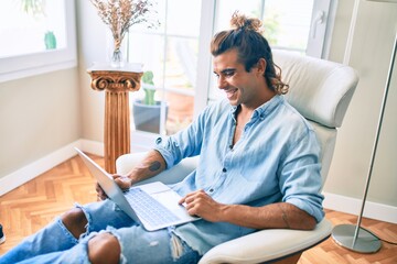 Young hispanic man smiling happy using laptop at home