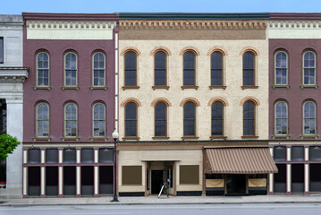 old fashioned small town main street facade with painted brick buildings - 397920792