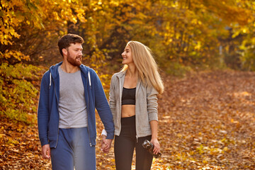 romantic young couple enjoying walk in the autumn sunny forest, contemplating the nature, yellow trees around. hiking, autumn forest, walking, love concept