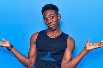 Young african american man wearing sportswear clueless and confused expression with arms and hands...