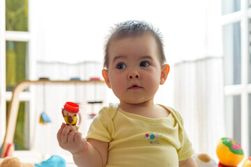 Bebe pequeño con juguetes en casa con vestido amarillo