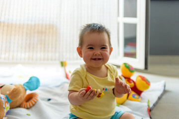 Bebe pequeño con juguetes en casa con vestido amarillo