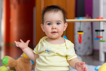 Bebe pequeño con juguetes en casa con vestido amarillo