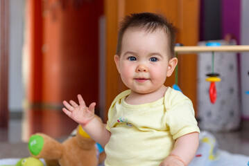 Bebe pequeño con juguetes en casa con vestido amarillo