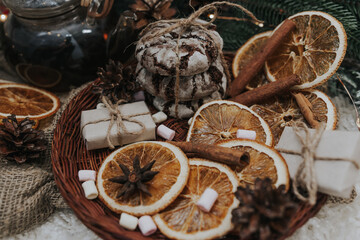 Still life details in home interior. Cozy winter concept with cinnamon, pine cones, cookies, marshmallows, garland and gifts