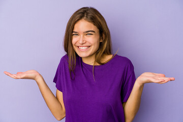 Young skinny caucasian girl teenager on purple background makes scale with arms, feels happy and confident.