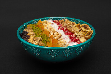 Closeup of traditional Turkish Dessert Asure or Ashura (aka Noah Pudding) in traditional green bowl isolated on black background.