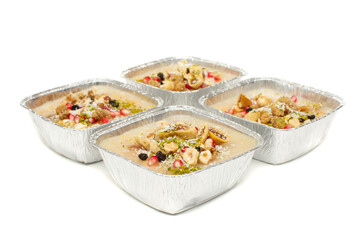 Closeup of traditional Turkish Dessert Asure or Ashura (aka Noah Pudding) in disposable aluminum bowls isolated on white background. with copy space for text. 