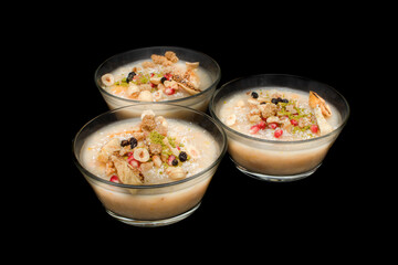 Closeup of traditional Turkish Dessert Asure or Ashura (aka Noah Pudding) in white bowls isolated on black backgroun