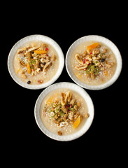 Closeup of traditional Turkish Dessert Asure or Ashura (aka Noah Pudding) in white bowls isolated on black backgroun