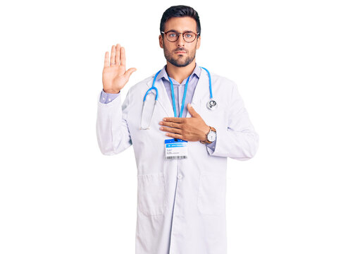 Young hispanic man wearing doctor uniform and stethoscope swearing with hand on chest and open palm, making a loyalty promise oath