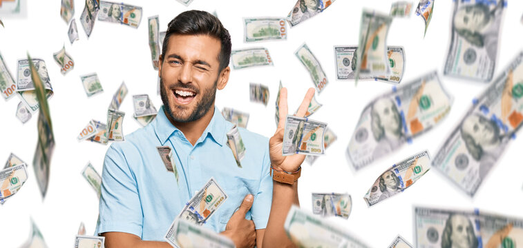 Handsome hispanic man wearing casual clothes smiling with happy face winking at the camera doing victory sign. number two.