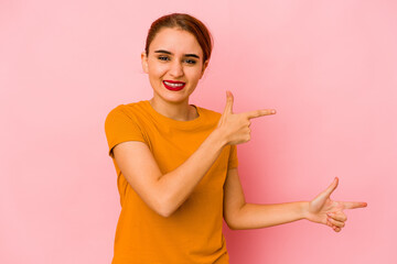 Young arab mixed race woman pointing with forefingers to a copy space, expressing excitement and desire.