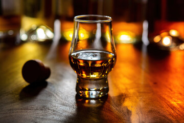 Dram of single malt scotch whisky and bottles on background