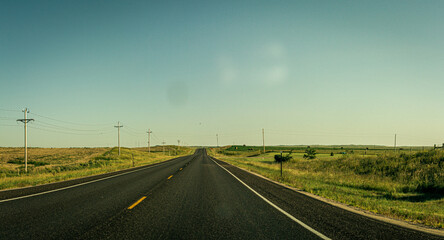 Wide shot of straight road through american nature with power line