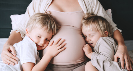 Pregnant woman with her children at home. Third pregnancy. Maternity, family, parenting concept.