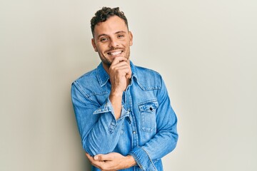 Fototapeta premium Young hispanic man wearing casual clothes smiling looking confident at the camera with crossed arms and hand on chin. thinking positive.
