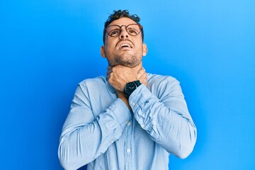 Young hispanic man wearing casual clothes and glasses shouting suffocate because painful strangle. health problem. asphyxiate and suicide concept.
