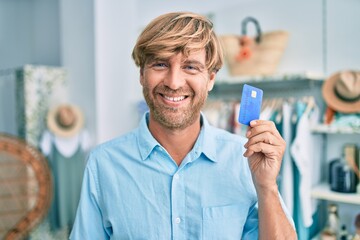 Handsome caucasian man smiling happy shopping on retail shop at the shopping center showing credit card