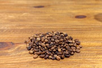 Pile of roasted artesanal gourmet coffee beans pattern on a wood table