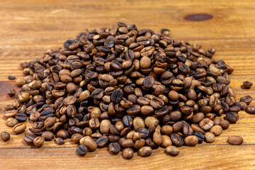 Pile of roasted artesanal gourmet coffee beans pattern on a wood table