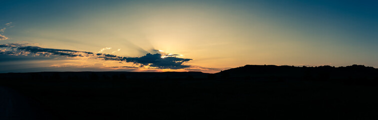Panorama shot of colorful sunset behind clouds in Badland national park in america