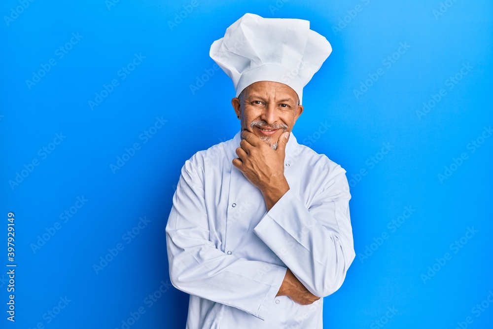 Canvas Prints Middle age grey-haired man wearing professional cook uniform and hat looking confident at the camera smiling with crossed arms and hand raised on chin. thinking positive.