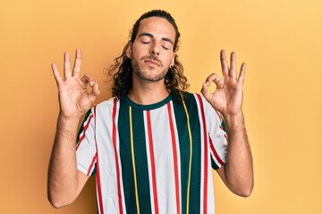 Young handsome man with long hair wearing casual clothes relax and smiling with eyes closed doing meditation gesture with fingers. yoga concept.