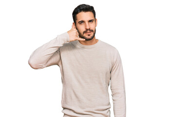 Young hispanic man wearing casual clothes smiling doing phone gesture with hand and fingers like talking on the telephone. communicating concepts.