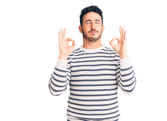 Naklejka premium Young hispanic man wearing casual clothes relaxed and smiling with eyes closed doing meditation gesture with fingers. yoga concept.
