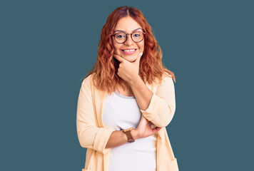 Young latin woman wearing business clothes looking confident at the camera smiling with crossed arms and hand raised on chin. thinking positive.