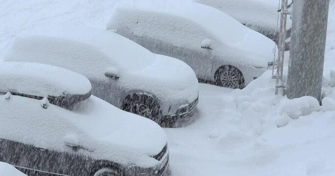 Snow falling on parking cars on a skiing resort, vehicles gerring buried