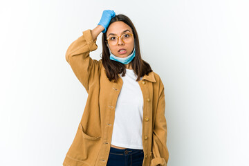 Young latin woman wearing a mask to protect from covid isolated on white background being shocked, she has remembered important meeting.