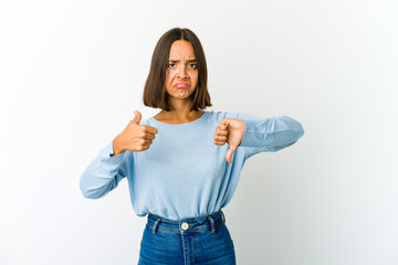 Young mixed race woman showing thumbs up and thumbs down, difficult choose concept