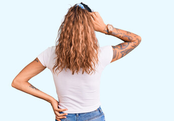Young hispanic woman with tattoo wearing casual white tshirt backwards thinking about doubt with hand on head
