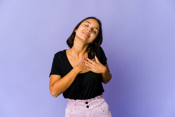 Young mixed race woman has friendly expression, pressing palm to chest. Love concept.