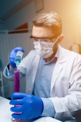 Young Scientist Checking Test Tubes In The Lab. Man Wears Protective Goggles