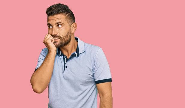 Handsome man with beard wearing casual clothes looking stressed and nervous with hands on mouth biting nails. anxiety problem.