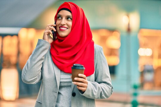 Young arab businesswoman talking on the smartphone and drinking coffee at the city.